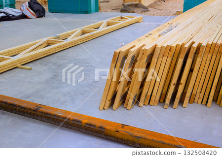 Neatly stacked wooden roofing joins planks nearby tools preparation for building at construction site. Neatly stacked wooden roofing joins planks nearby tools preparation for building at construction site. 132508420
