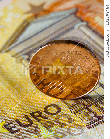 Five euro cent coin standing on fifty euro banknote, symbol of European savings and economy Five euro cent coin standing on fifty euro banknote, symbol of European savings and economy 132508464