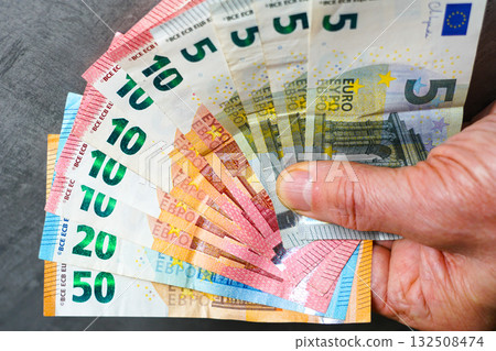Hand holding small amount of euro banknotes symbolizing modest income, savings, and financial limits 132508474