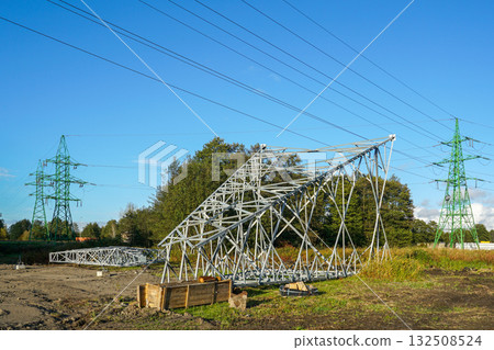 New electricity transmission tower under construction near green pylons and power lines on clear day 132508524