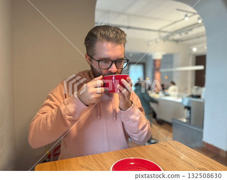 Man drinking coffee at cafe table. Quiet moment of warmth, reflection and simple pleasure during daily routine. Man drinking coffee at cafe table. Quiet moment of warmth, reflection and simple pleasure during daily routine. 132508630
