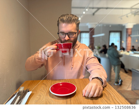Man sipping coffee in stylish cafe. Focused moment of taste, aroma and mindful enjoyment during morning break. Man sipping coffee in stylish cafe. Focused moment of taste, aroma and mindful enjoyment during morning break. 132508636