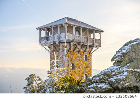 A stunning lookout tower sits on Wysoki Kamien in the Jizera Mountains, surrounded by snow-covered trees. The clear sky enhances the beauty of this winter landscape. A stunning lookout tower sits on Wysoki Kamien in the Jizera Mountains, surrounded by snow-covered trees. The clear sky enhances the beauty of this winter landscape. 132508664