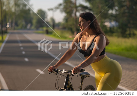 Curvy Caucasian Woman Riding Bicycle in Park.  132509398