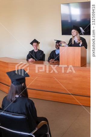 A young woman stands at the lectern and delivers a graduation speech to her classmates.  132509418