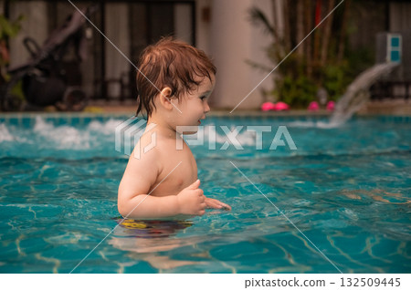 Caucasian one year old boy playing ball in swimming pool.  132509445