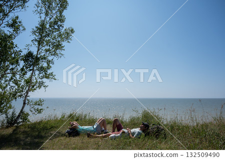 Caucasian couple relaxing during a hike on the seashore.  132509490