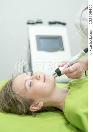 Caucasian woman undergoing radio wave RF lifting procedure in beauty salon. Caucasian woman undergoing radio wave RF lifting procedure in beauty salon. 132509493