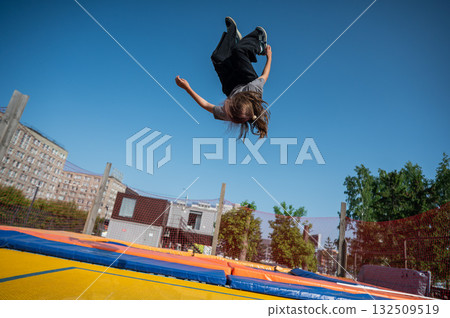A girl jumps on an outdoor trampoline. A girl jumps on an outdoor trampoline. 132509519