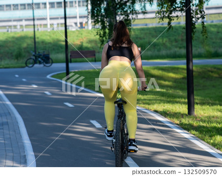 Curvy Caucasian Woman Riding Bicycle in Park.  132509570