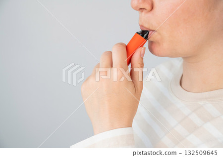 Caucasian woman smoking disposable vape.  132509645