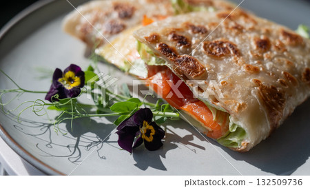 A flatbread stuffed with fish and cheese served in a cafe. Quesadilla. A flatbread stuffed with fish and cheese served in a cafe. Quesadilla. 132509736