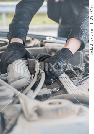 A man changes spark plugs in his car. A man changes spark plugs in his car. 132509752