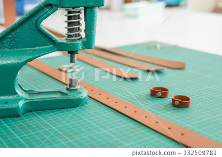 A woman attaches accessories to a leather belt. Leatherworker's workshop. A woman attaches accessories to a leather belt. Leatherworker's workshop. 132509781