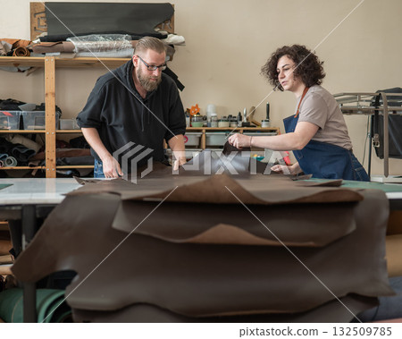 A man and a woman work as tanners in a workshop. A man and a woman work as tanners in a workshop. 132509785