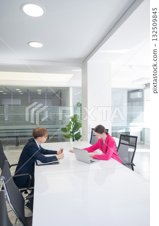 Man and woman talking while sitting at desk in office. Man and woman talking while sitting at desk in office. 132509845