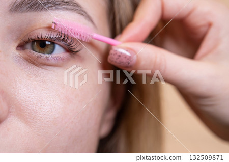 Caucasian woman brushing her eyelashes after lamination.  132509871