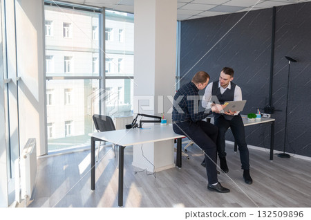 Two Caucasian men discussing work in an office. Businessman with a hearing aid.  132509896