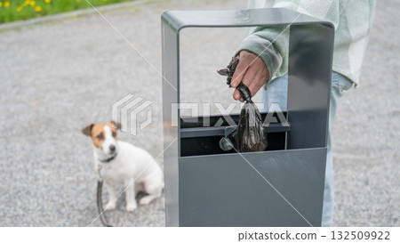 Responsible Dog Owner Disposing of Waste in Park Bin.  132509922
