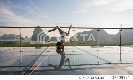 Caucasian woman doing forearm stand on glass bridge among mountains. Caucasian woman doing forearm stand on glass bridge among mountains. 132509955