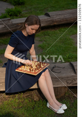 Caucasian woman playing chess outdoors. Caucasian woman playing chess outdoors. 132509976