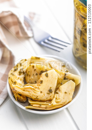 Pickled artichoke in bowl on white table. 132510003