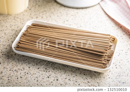Buckwheat soba noodles on plate on kitchen table. Buckwheat soba noodles on plate on kitchen table. 132510010