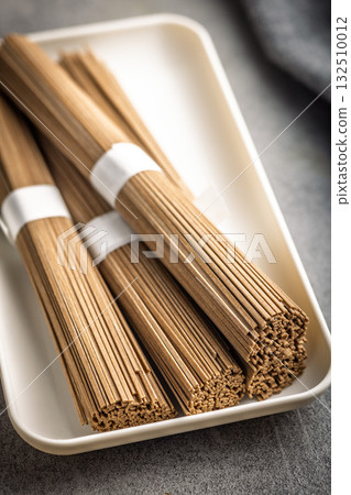 Buckwheat soba noodles on plate on kitchen table. Buckwheat soba noodles on plate on kitchen table. 132510012