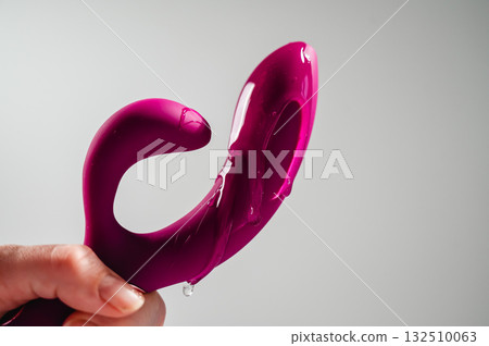 Lube pouring on pink dildo on white background. Lube pouring on pink dildo on white background. 132510063