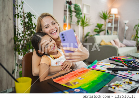 Mother and daughter enjoy a creative art session at home, capturing a joyful selfie Mother and daughter enjoy a creative art session at home, capturing a joyful selfie 132510115