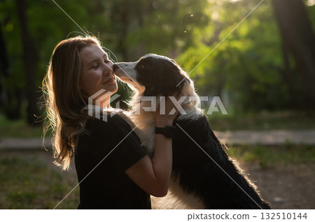 Young Caucasian woman hugging her border collie dog while walking in the park. Young Caucasian woman hugging her border collie dog while walking in the park. 132510144