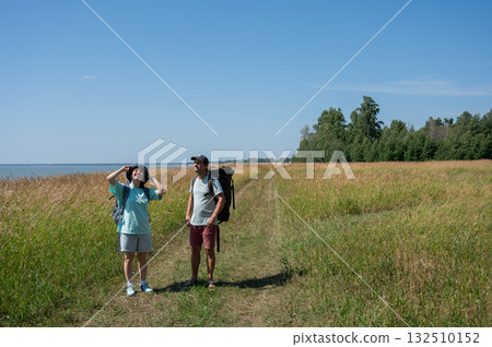Caucasian couple hiking with backpacks on the seashore.  132510152