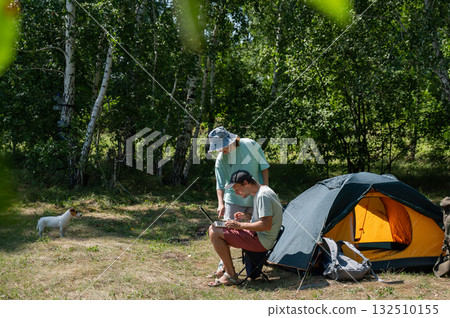 Caucasian man working on laptop in camping. Couple relaxing in nature. Caucasian man working on laptop in camping. Couple relaxing in nature. 132510155