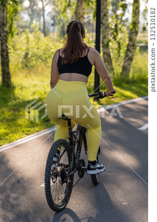 Curvy Caucasian Woman Riding Bicycle in Park.  132510182