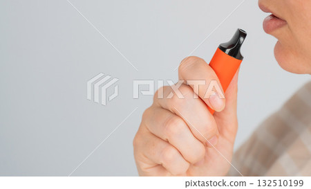 Caucasian woman smoking disposable vape.  132510199