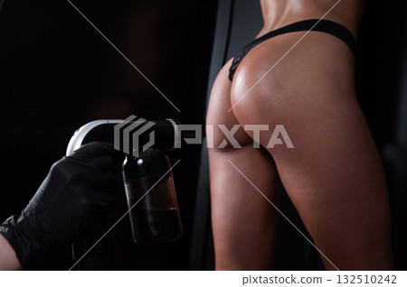 The master applies tinting paint on the back of a woman. Instant tanning treatment. The master applies tinting paint on the back of a woman. Instant tanning treatment. 132510242