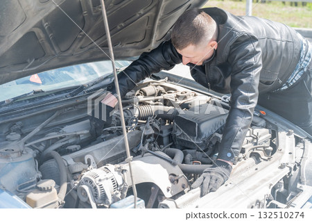 A man changes spark plugs in his car.  132510274