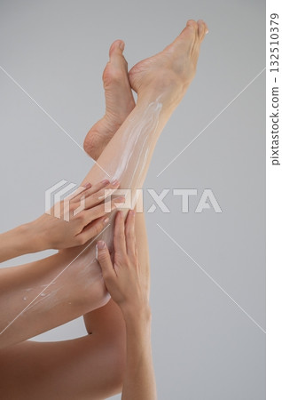 Woman applying moisturizer to her legs. White background. Woman applying moisturizer to her legs. White background. 132510379