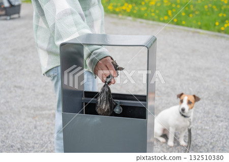 Responsible Dog Owner Disposing of Waste in Park Bin. Responsible Dog Owner Disposing of Waste in Park Bin. 132510380