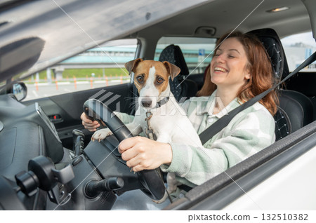 Caucasian woman traveling by car with her dog.  132510382