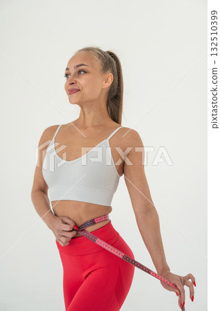 Young woman measuring her waist on white background. 132510399