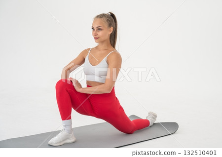 Young woman doing splits exercises on white background. Young woman doing splits exercises on white background. 132510401