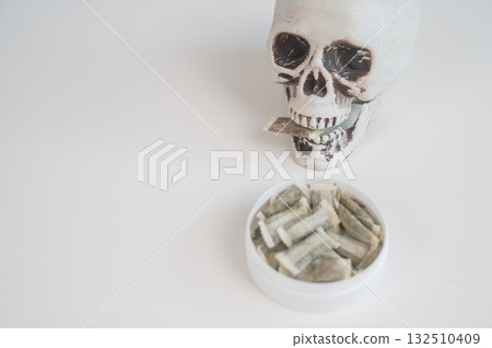 Skull Chewing Tobacco on a White Table. Skull Chewing Tobacco on a White Table. 132510409