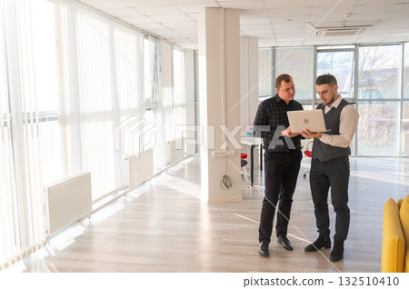 Two Caucasian men looking at a laptop and discussing work. Two Caucasian men looking at a laptop and discussing work. 132510410