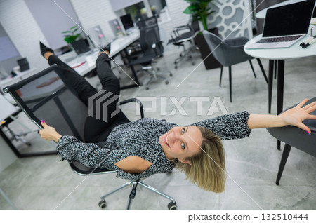 Caucasian woman having fun and lying on office chair. Caucasian woman having fun and lying on office chair. 132510444