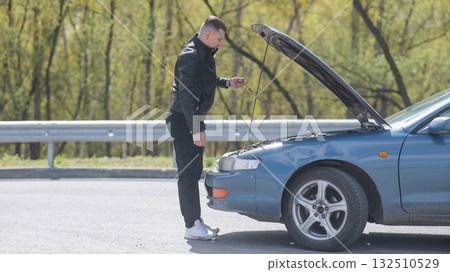 Caucasian man checking engine oil level in his car.  132510529