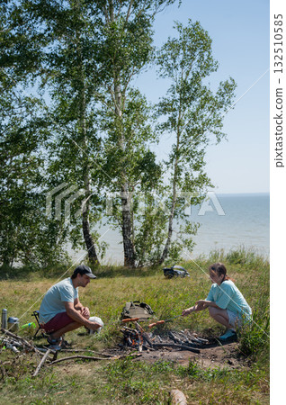 Caucasian couple roasting sausages over a fire. Caucasian couple roasting sausages over a fire. 132510585