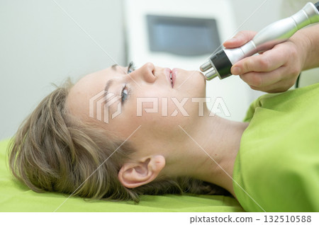 Caucasian woman undergoing radio wave RF lifting procedure in beauty salon. Caucasian woman undergoing radio wave RF lifting procedure in beauty salon. 132510588