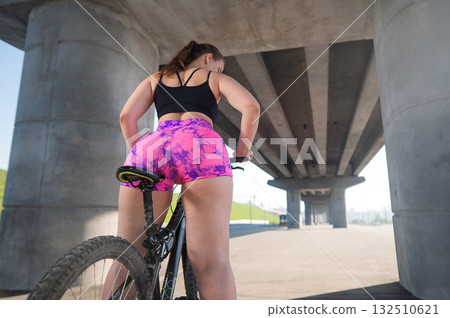 Caucasian woman in short shorts riding a bicycle.  132510621