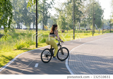 Curvy Caucasian Woman Riding Bicycle in Park. Curvy Caucasian Woman Riding Bicycle in Park. 132510631